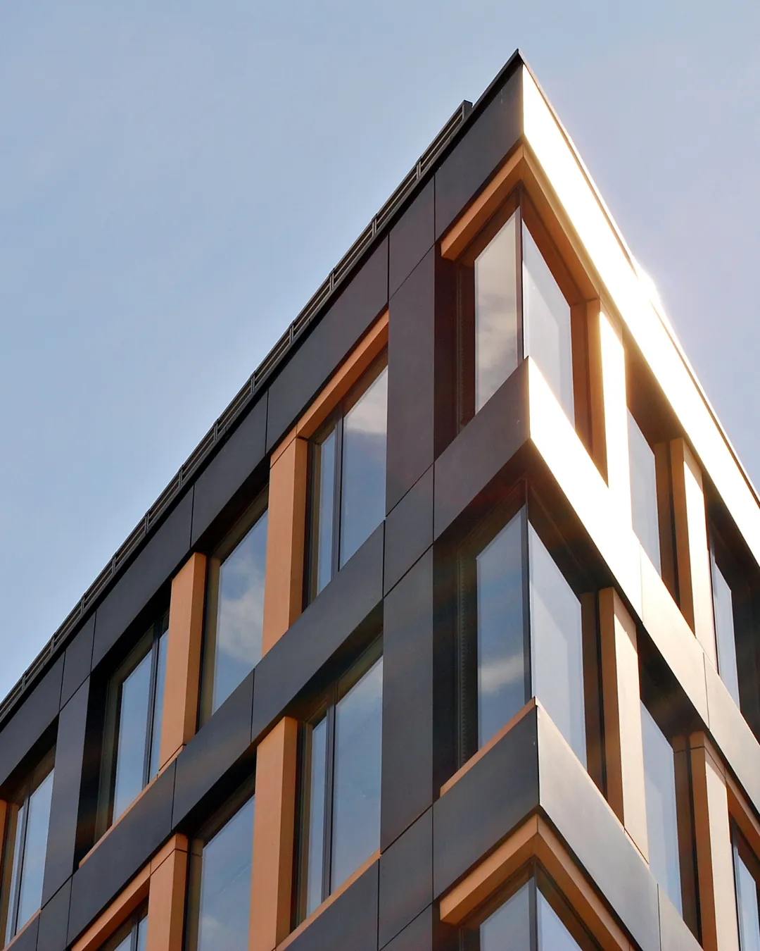 Façade contemporaine en verre et cuivre d'un immeuble — deRham, régie immobilière